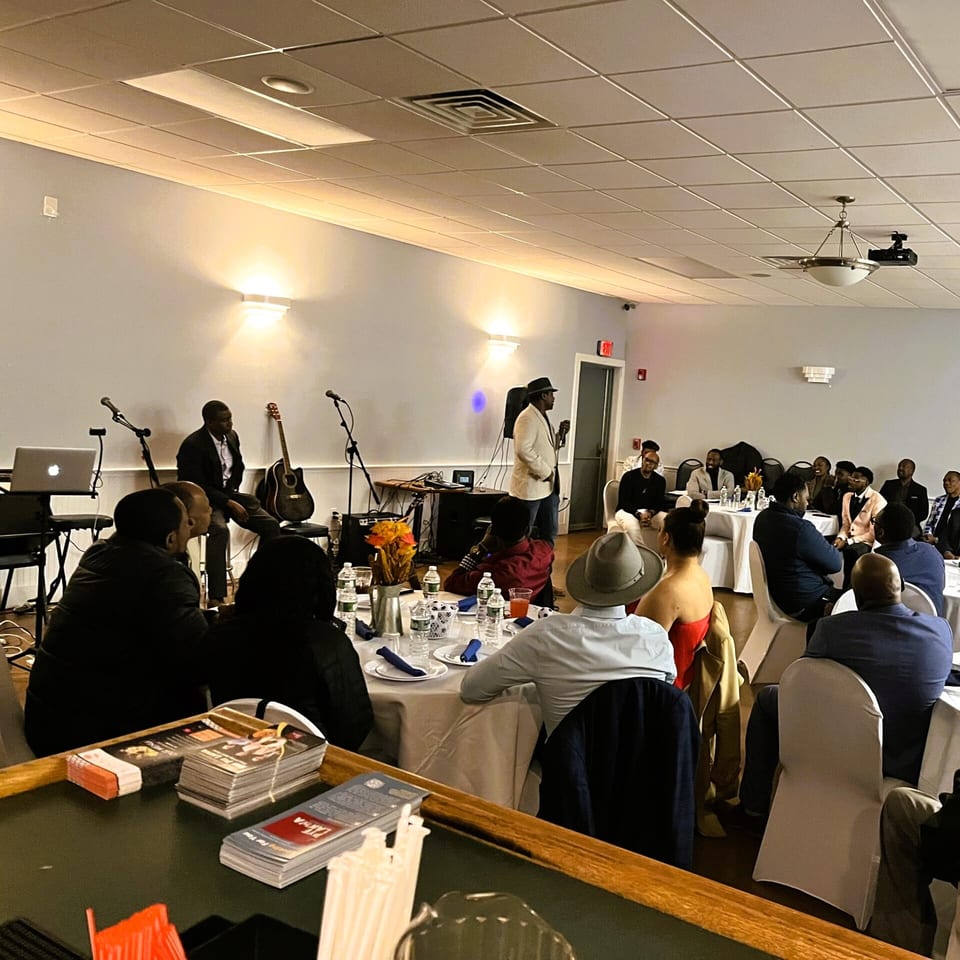 A speaker addresses a seated audience at Ethno Caribbean Cuisine, with musical instruments on stage.
